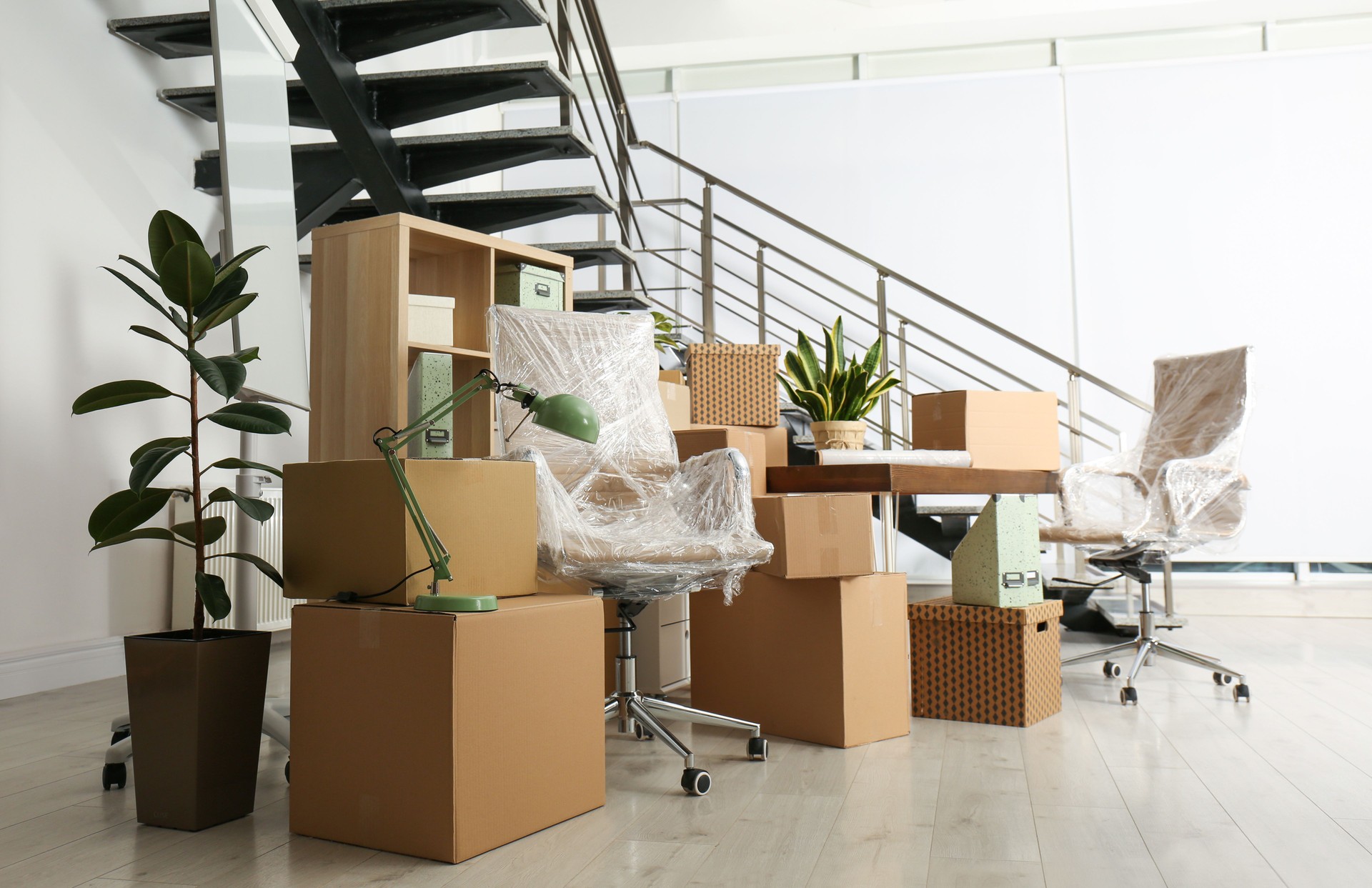 Cardboard boxes and furniture near stairs in office. Moving day